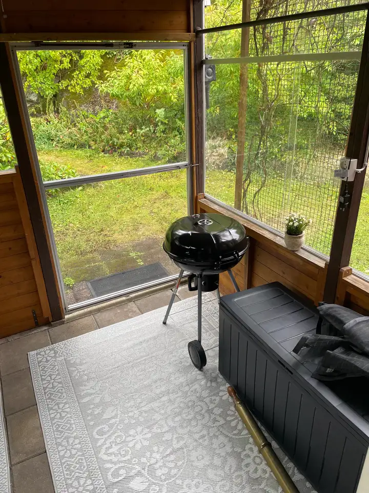 Wintergarten mit Holzkohlegrill und Blick auf den Rasen